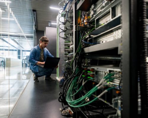 Latin American computer technician fixing a network server the office - focus on foreground